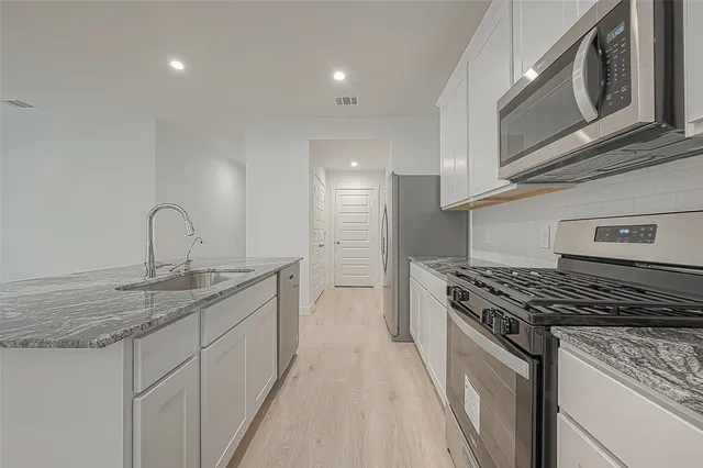 a kitchen with stainless steel appliances granite countertop a sink and a refrigerator