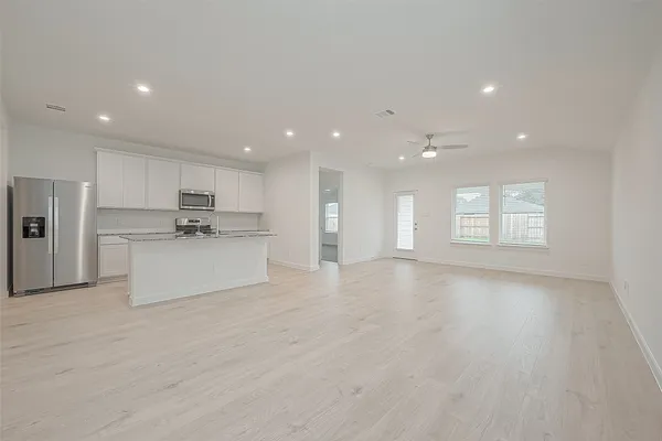 a view of kitchen with kitchen island sink refrigerator and white cabinets