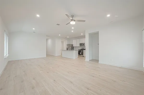 a view of a kitchen with kitchen island a sink wooden floor and a refrigerator