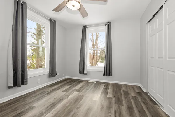 an empty room with wooden floor and windows