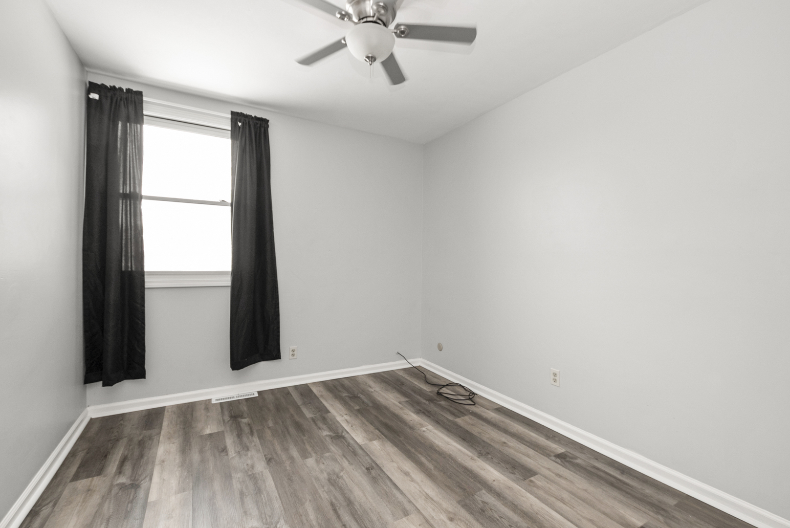 8340 West Lincoln Highway, Unit 8340 Frankfort, IL 60423 - Photo 8 of 12 an empty room with wooden floor and fan