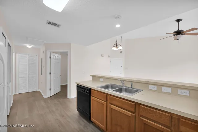 a view of a kitchen with a sink dishwasher a refrigerator and wooden floor