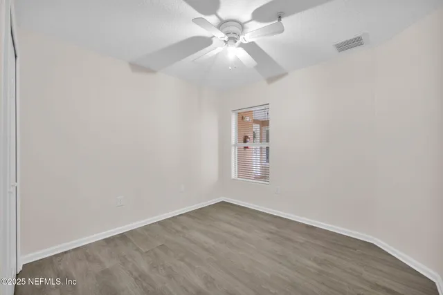 an empty room with a chandelier fan and windows