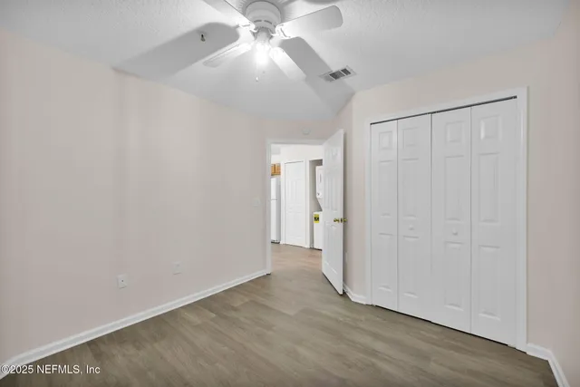an empty room with wooden floor fan and windows
