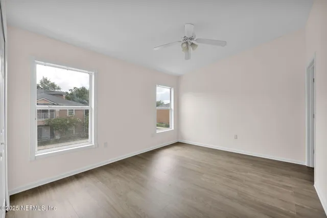 a view of an empty room with wooden floor and a window