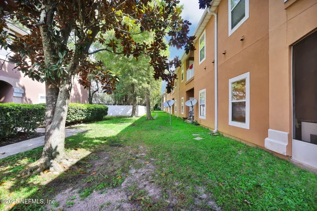 a view of a lake with a yard and large trees