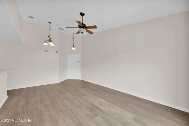 a view of a room with wooden floor and a ceiling fan