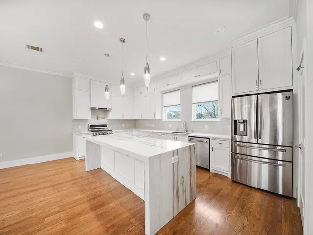 a kitchen with a refrigerator a sink dishwasher and a stove with wooden floor