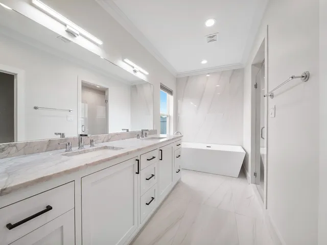 a bathroom with a granite countertop double vanity sink a mirror and a bathtub