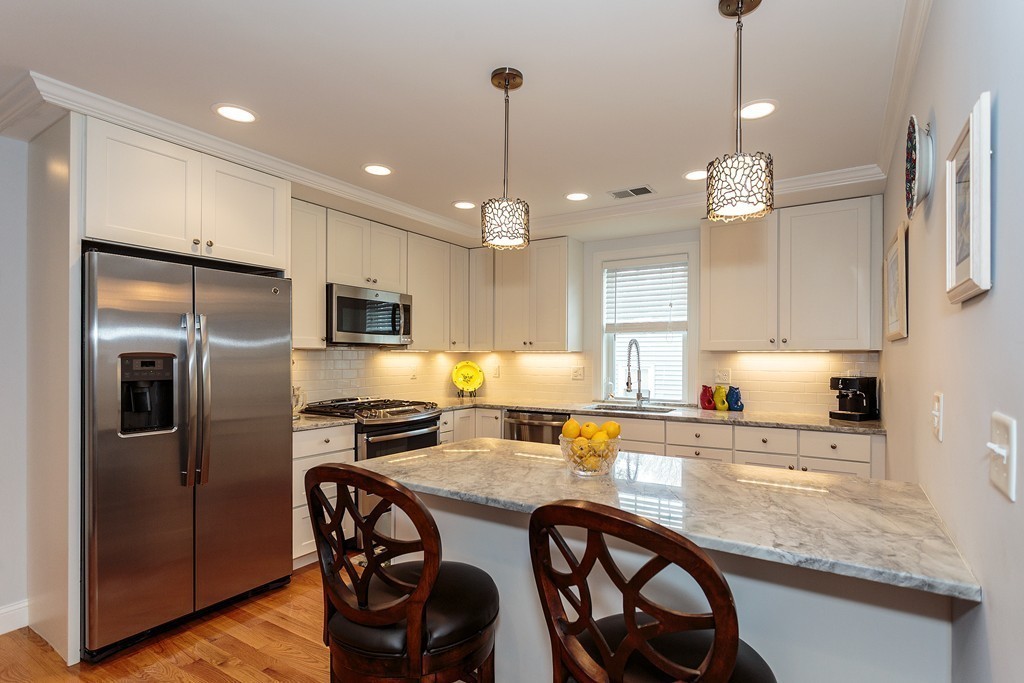 40 Catherine Street, Unit 2 Boston, MA 02131 - Photo 1 of 26 a kitchen with stainless steel appliances granite countertop a refrigerator a stove a sink dishwasher a dining table and chairs with wooden floor