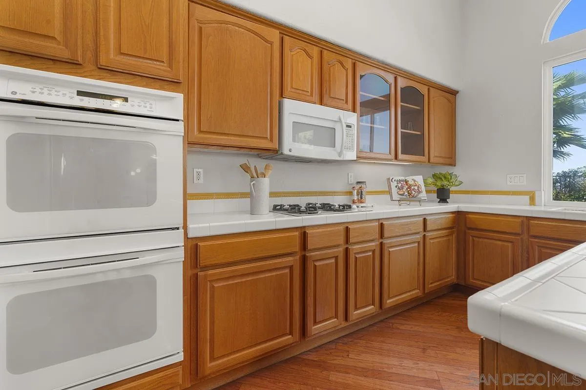 987 Palencia Court Chula Vista, CA 91910 - Photo 22 of 70 a kitchen with stainless steel appliances granite countertop a sink dishwasher a stove and cabinets with wooden floor