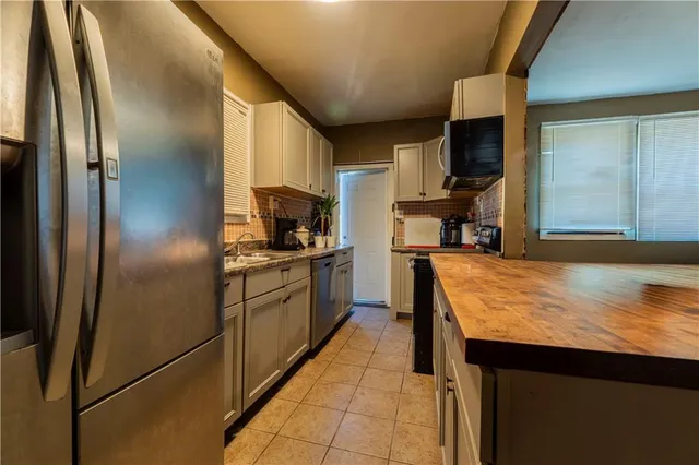 a kitchen with stainless steel appliances granite countertop a refrigerator a sink and a stove
