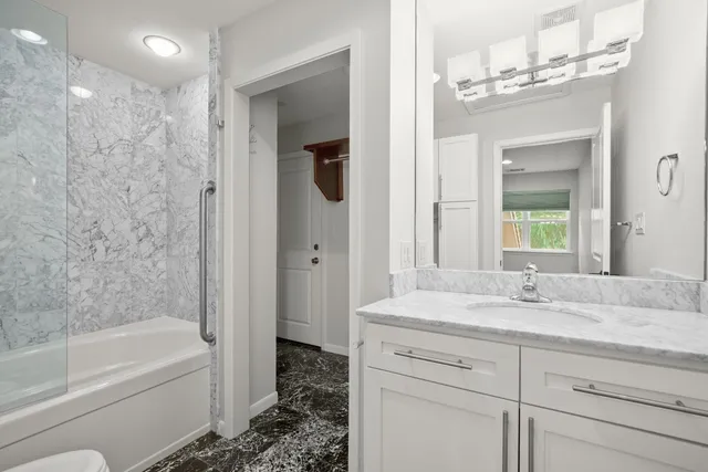 a bathroom with a granite countertop sink a toilet and shower