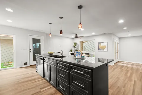 a kitchen with stainless steel appliances granite countertop a sink a stove and a wooden floors