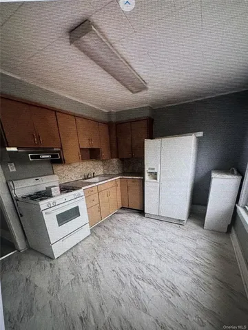 a kitchen with a sink white cabinets and white appliances