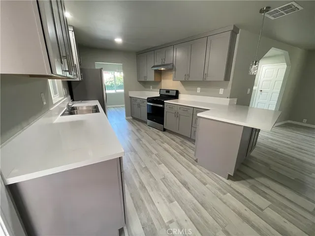 a kitchen with a sink stainless steel appliances wooden floor and cabinets
