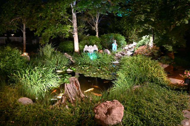 314 Brown Farm Lane Draper, UT 84020 - Photo 53 of 57 Tranquil water feature with a koi pond, cascading waterfall, and mature trees, enhanced by integrated landscape lighting