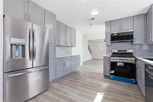 a kitchen with stainless steel appliances a refrigerator a stove and a wooden floors