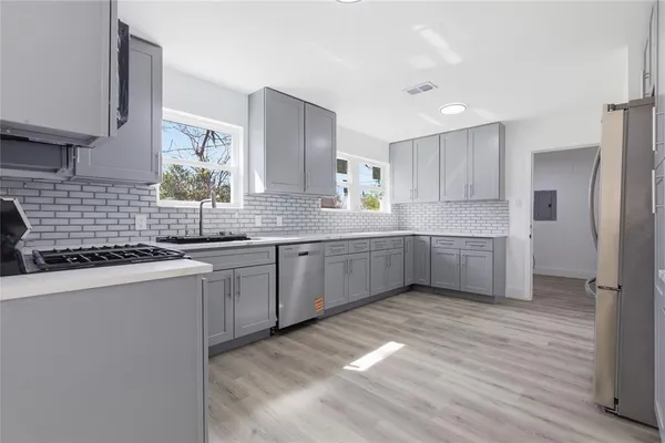 a kitchen with stainless steel appliances a sink a stove a refrigerator and cabinets