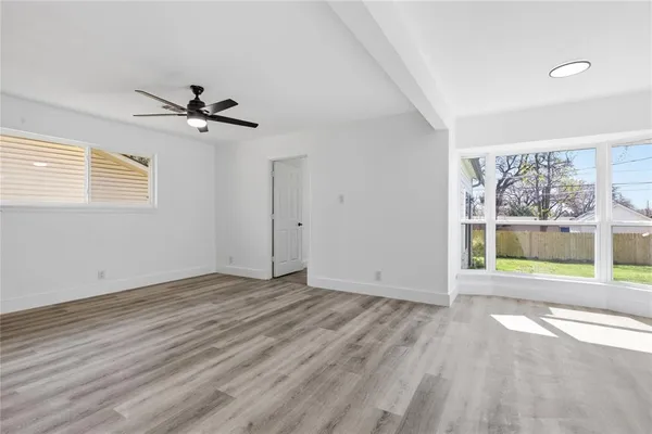 a view of an empty room with a window and wooden floor
