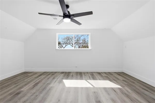 an empty room with wooden floor and a ceiling fan
