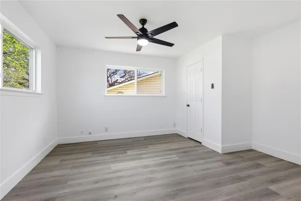 an empty room with wooden floor and ceiling fan