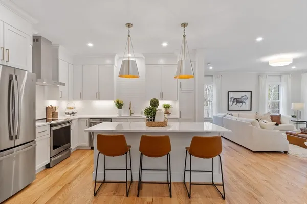 a kitchen with stainless steel appliances kitchen island granite countertop a dining table chairs and white cabinets