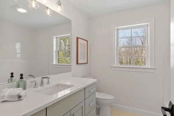 a bathroom with a granite countertop sink a large mirror a toilet and a window