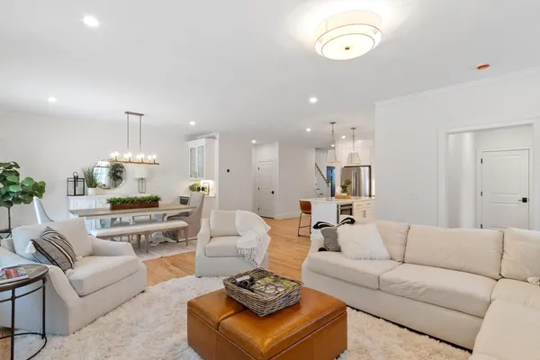 a living room with furniture kitchen view and a chandelier