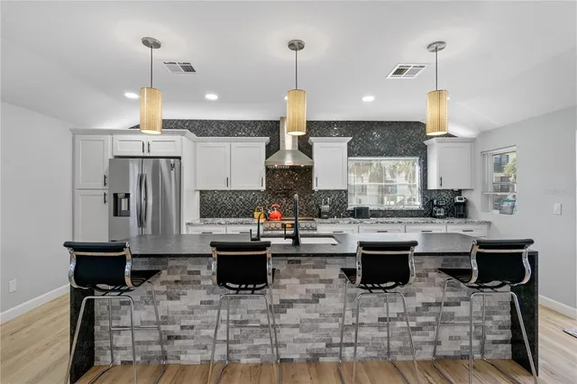a kitchen with stainless steel appliances granite countertop a sink a stove and a flat screen tv