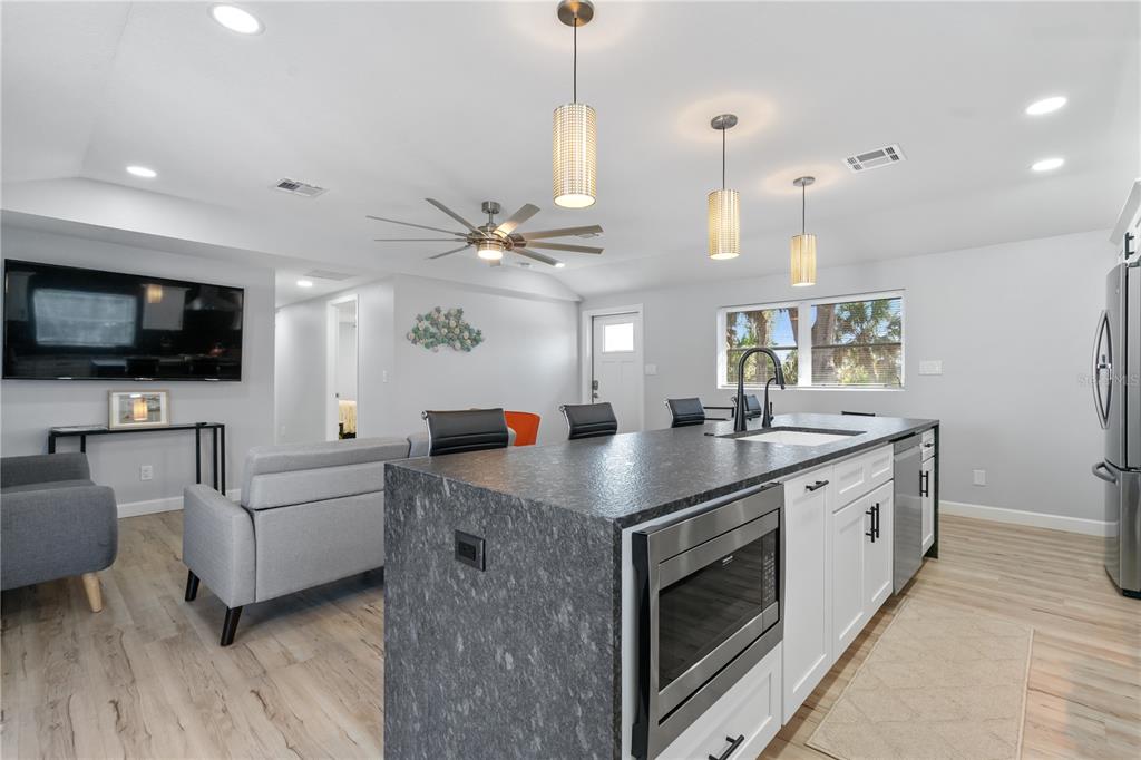 2476 North Beach Road Englewood, FL 34223 - Photo 13 of 58 a kitchen with stainless steel appliances granite countertop a sink a stove and a flat screen tv