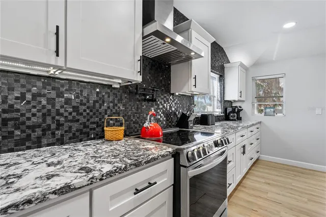 a kitchen with stainless steel appliances granite countertop a sink dishwasher a stove with a dining table and chairs