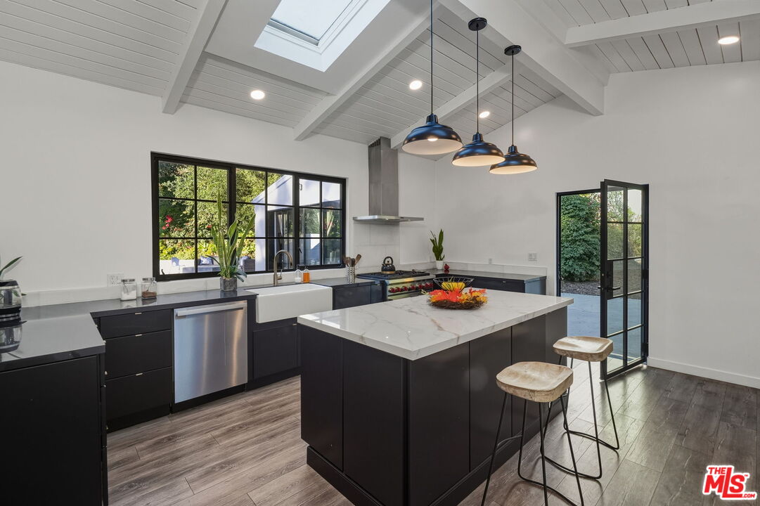 13019 Sky Valley Road Los Angeles, CA 90049 - Photo 16 of 39 a kitchen with a stove a refrigerator a sink dishwasher with a dining table and chairs with wooden floor