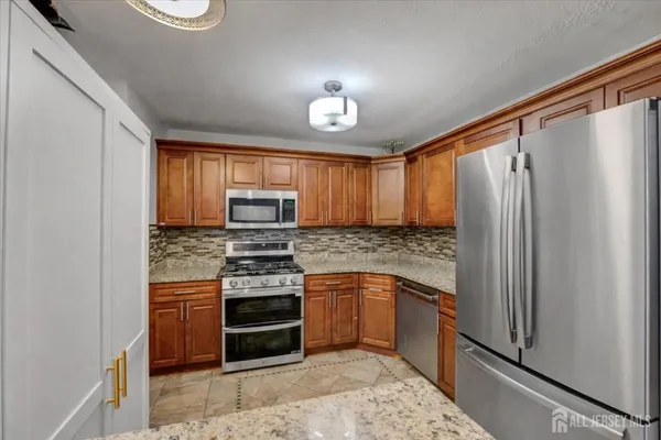 a kitchen with stainless steel appliances granite countertop a stove a refrigerator and a sink
