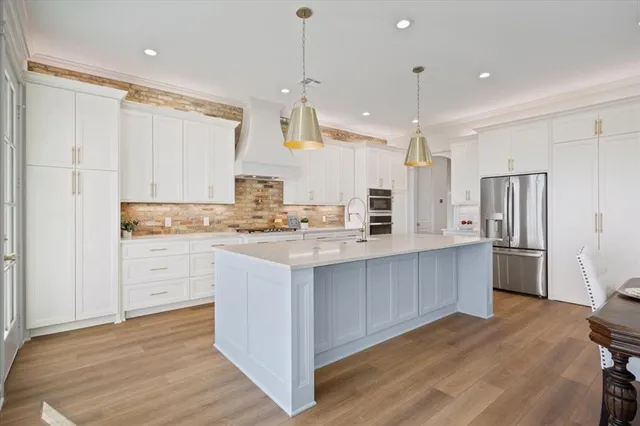 a large kitchen with white cabinets stainless steel appliances and wooden floor