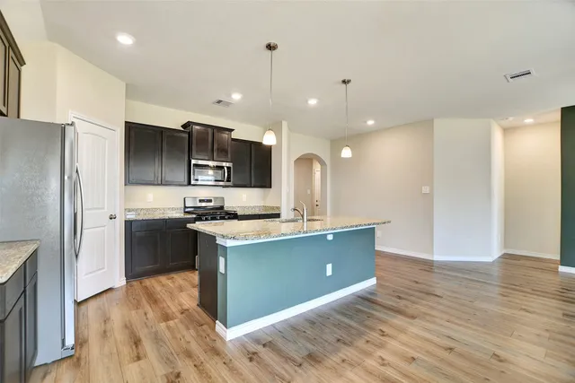 a kitchen with kitchen island stainless steel appliances a sink cabinets and wooden floor