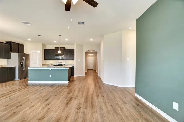 a large kitchen with kitchen island a sink dishwasher a stove and a refrigerator with wooden floor