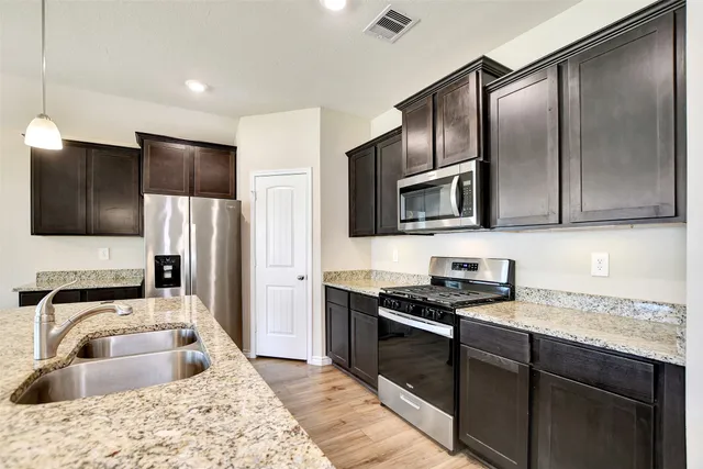 a kitchen with granite countertop stainless steel appliances a refrigerator sink and microwave
