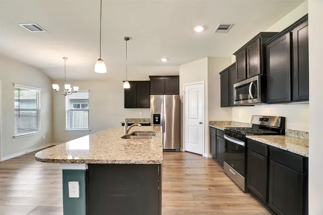 a kitchen with granite countertop stainless steel appliances and wooden floor