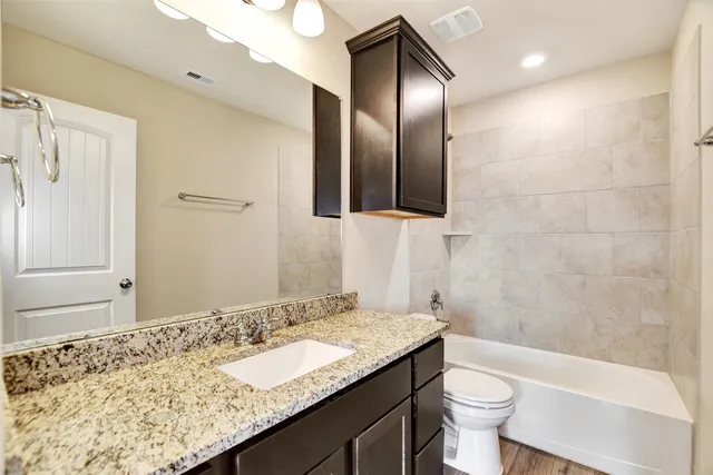 a bathroom with a granite countertop sink toilet and shower