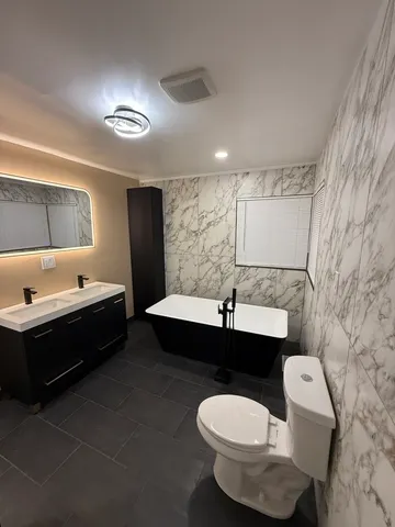 a bathroom with a bathtub sink mirror vanity and toilet