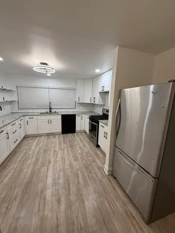 a kitchen with stainless steel appliances a refrigerator and wooden floor