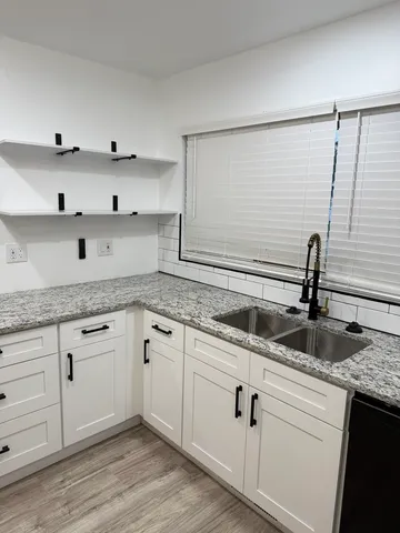 a kitchen with granite countertop white cabinets and a sink