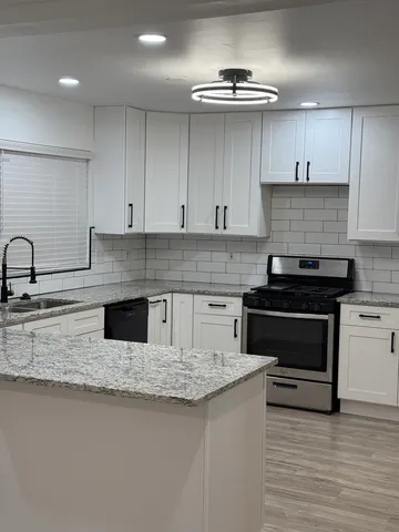 a kitchen with stainless steel appliances granite countertop a sink stove and cabinets
