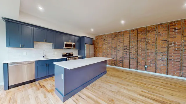 a large kitchen with stainless steel appliances granite countertop a sink stove and wooden floor