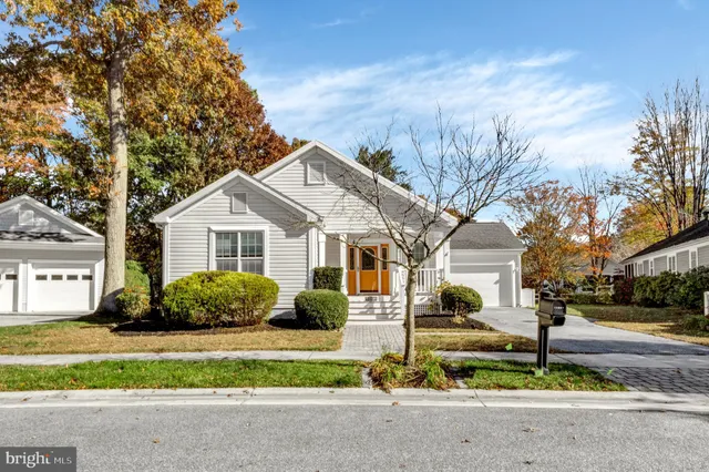 a view of a white house with a yard and large trees