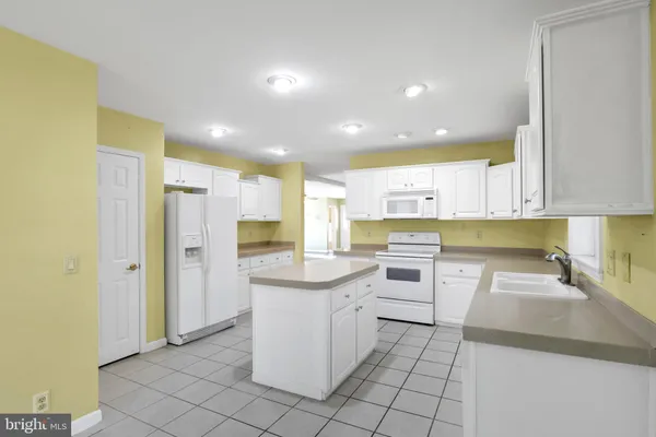 a kitchen that has a lot of white cabinets and stainless steel appliances