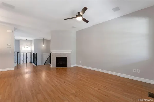a view of a livingroom with a fireplace a ceiling fan and windows