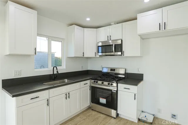a kitchen with granite countertop white cabinets sink and stainless steel appliances