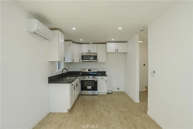 a kitchen with stainless steel appliances granite countertop a stove top oven a sink and a refrigerator